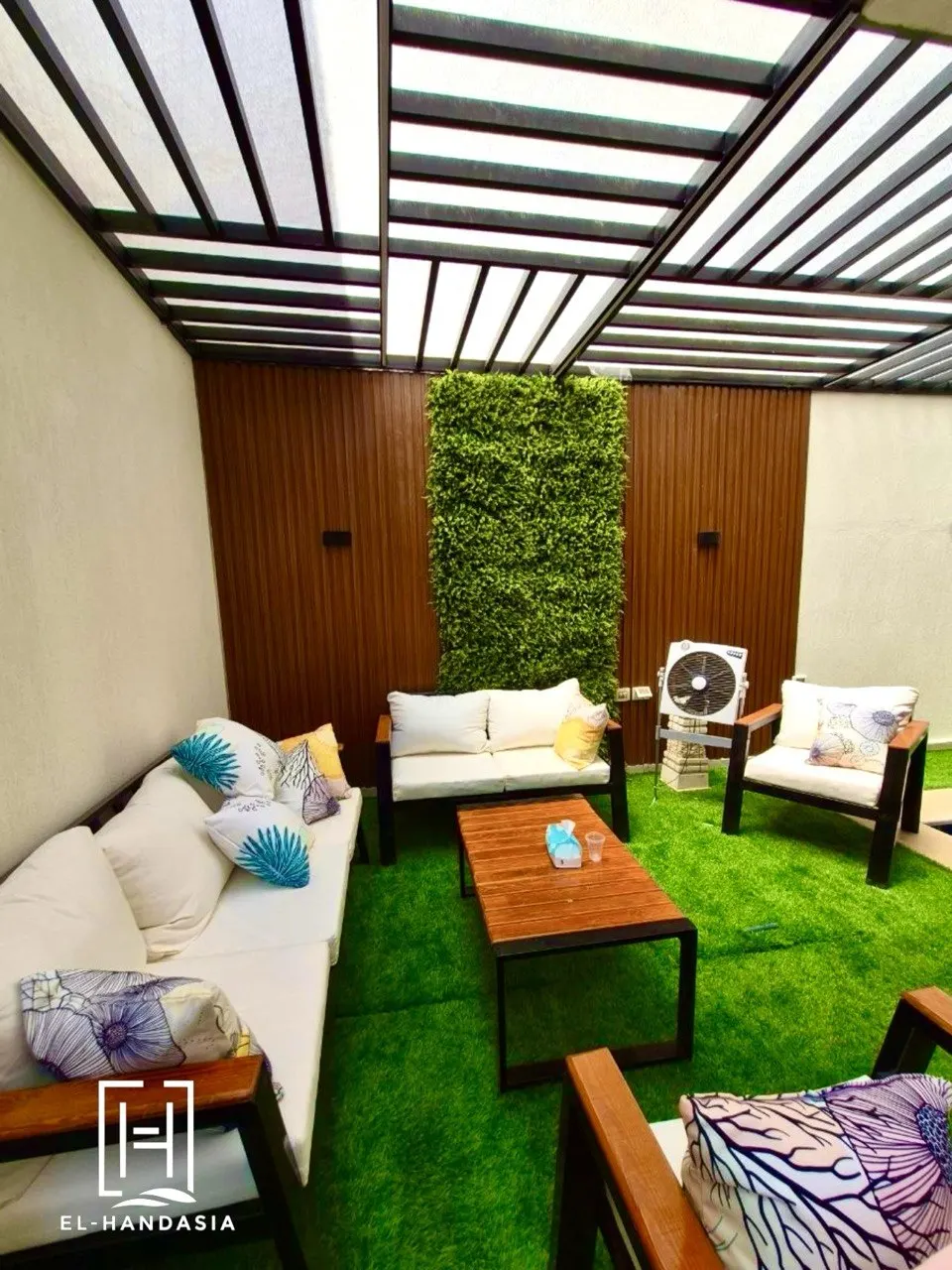 Shaded seating under the pergola beside the green wall