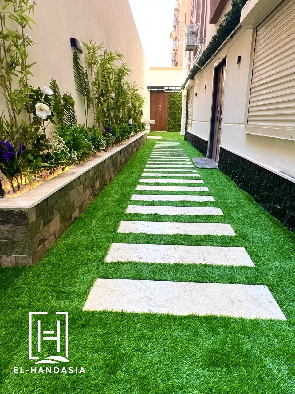 Travertine stepping slabs set into turf with a raised stone planter bed